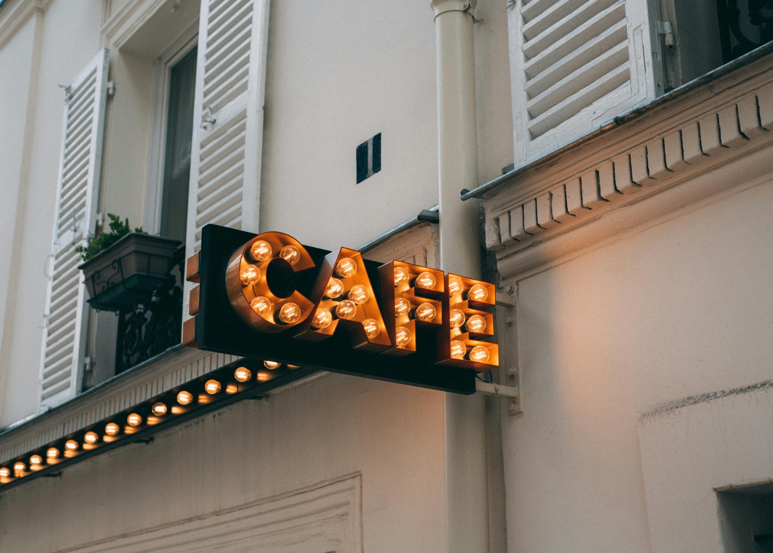 Elegant café sign with glowing bulbs, capturing the essence of Parisian architecture.